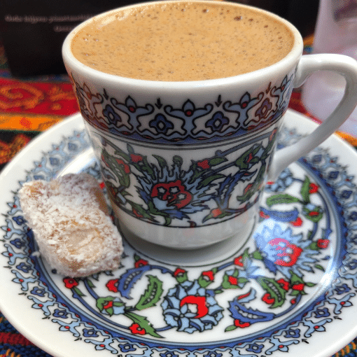 Turkish Coffee in a traditional tulip painted cup with a small turkish delight on the side. 