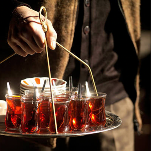 A man carrying the traditional carrying tray of Turkish tea to be distributed to the patrons