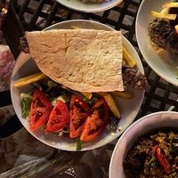 Adana Kebap served with tomatoes and Turkish flatbread