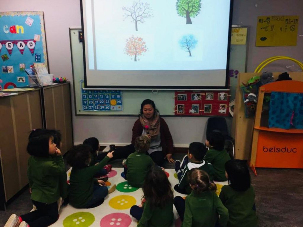 Pafoua and children sitting on a mat in a children's classroom