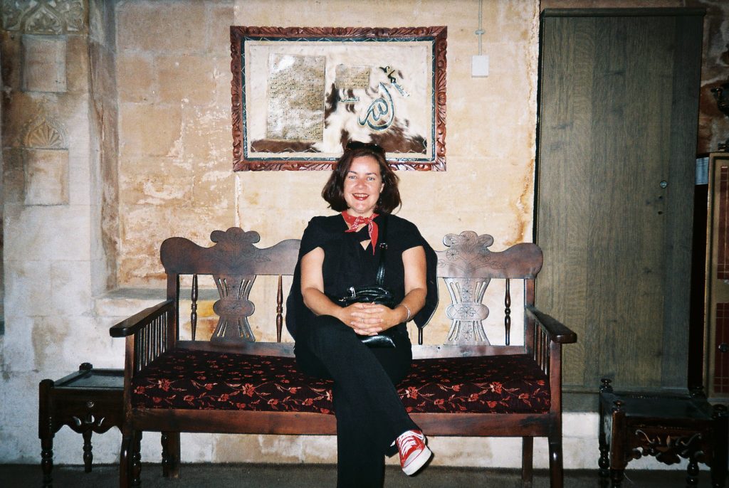 LIsa Morrow sitting on an old wooden bench in an entry way while in Mardin