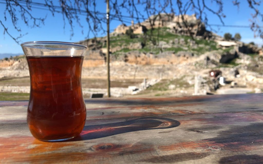 a small glass of Turkish Tea while sitting at a high table with Tlos in the background