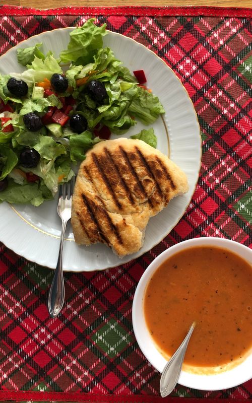 Tomato soup and salad with a piece of bread on a christmasy american service. 