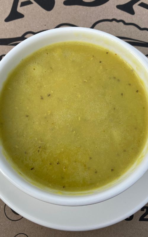 Lentil Soup in a white bowl with a service plate. 