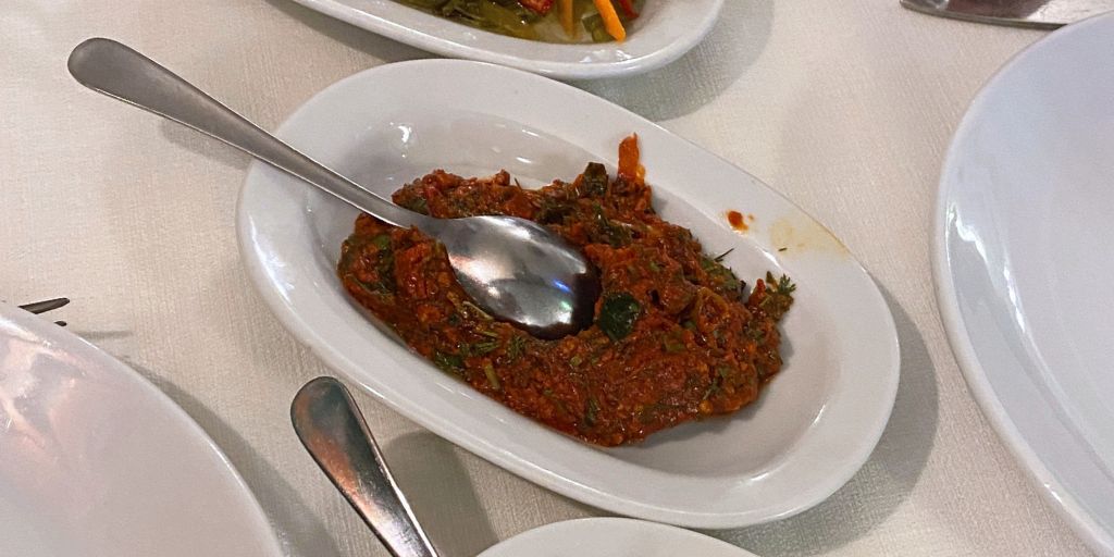 a Turkish appetizer and salad with tomatoes, green peppers, garlic, onions, parsley, pepper paste, lemon juice, olive oil, pomegranate syrup, mint, red pepper and salt.