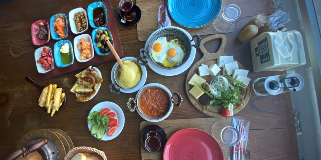 Turkish breakfast with mihlama, cheeses, eggs, honey and butter, olives, cucumbers, tomatoes, potatoes, borek and cay