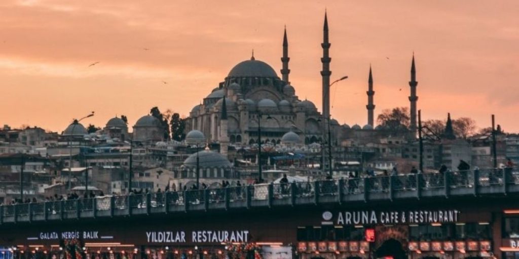 a mosque at sunset with seagulls flying all around taken from a boat. 