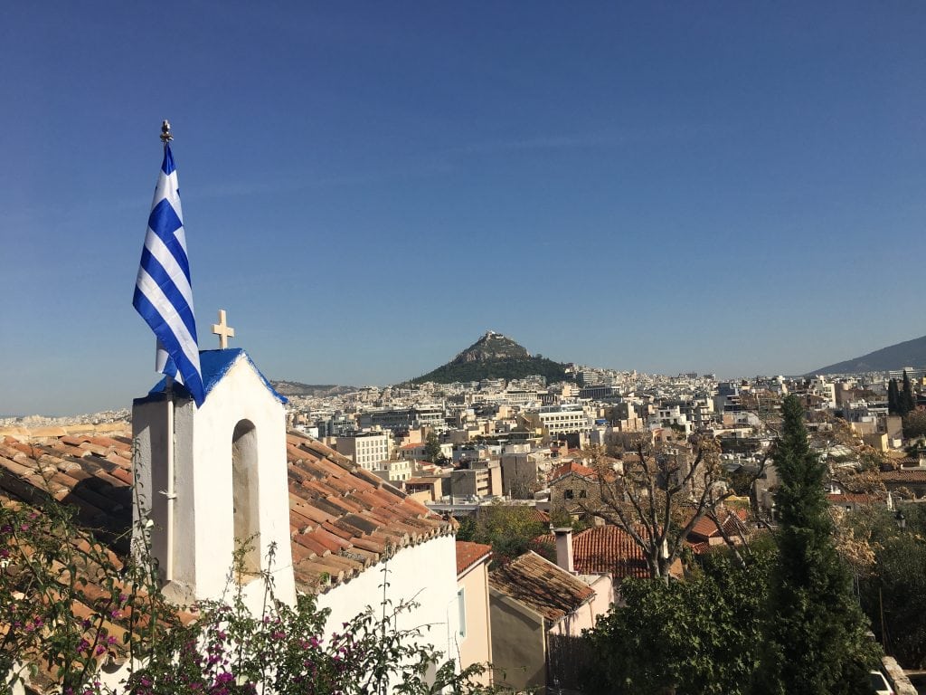 Greek flag atop a church overlooking the city