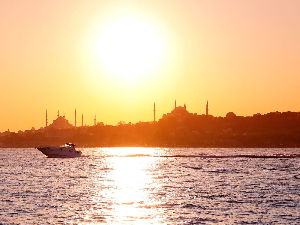 Sunrise over the European side of Istanbul with a small yacht on the water. 