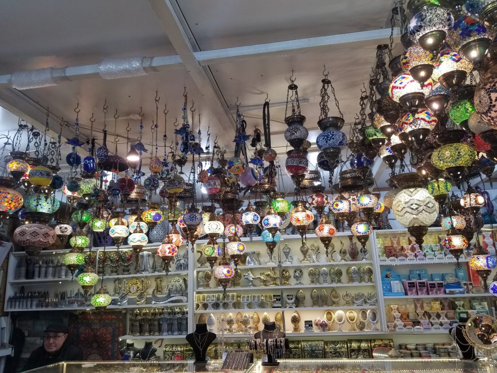 Turkish lamps hanging from a ceiling in a local shop. Along the walls are vases and other trinkets to buy