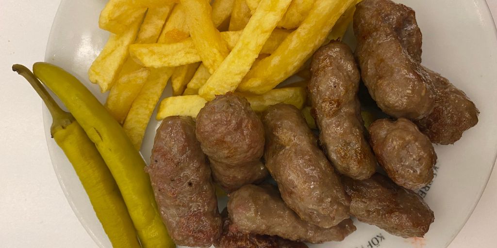 Inegol kofte with french fries and two green peppers on a plate