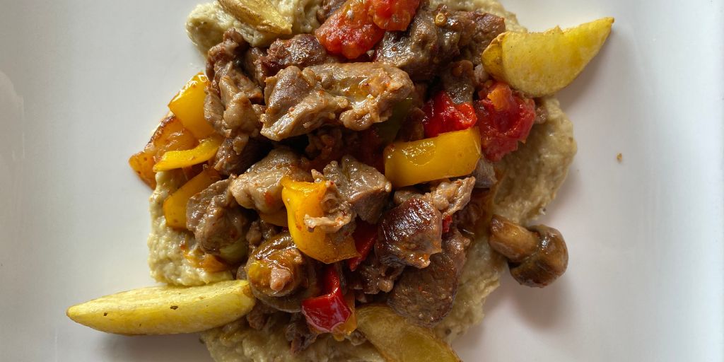 Hunkar Beğendİ Kebabı - diced meat with vegetables served a top of an eggplant puree garnished with potato wedges