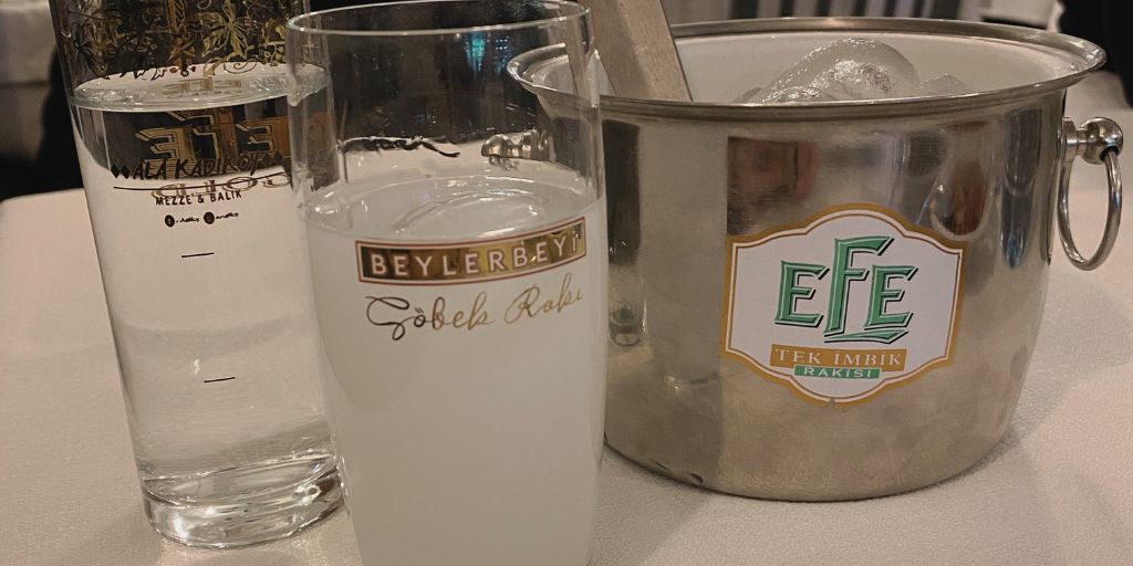 a glass of raki next to an  ice bucket