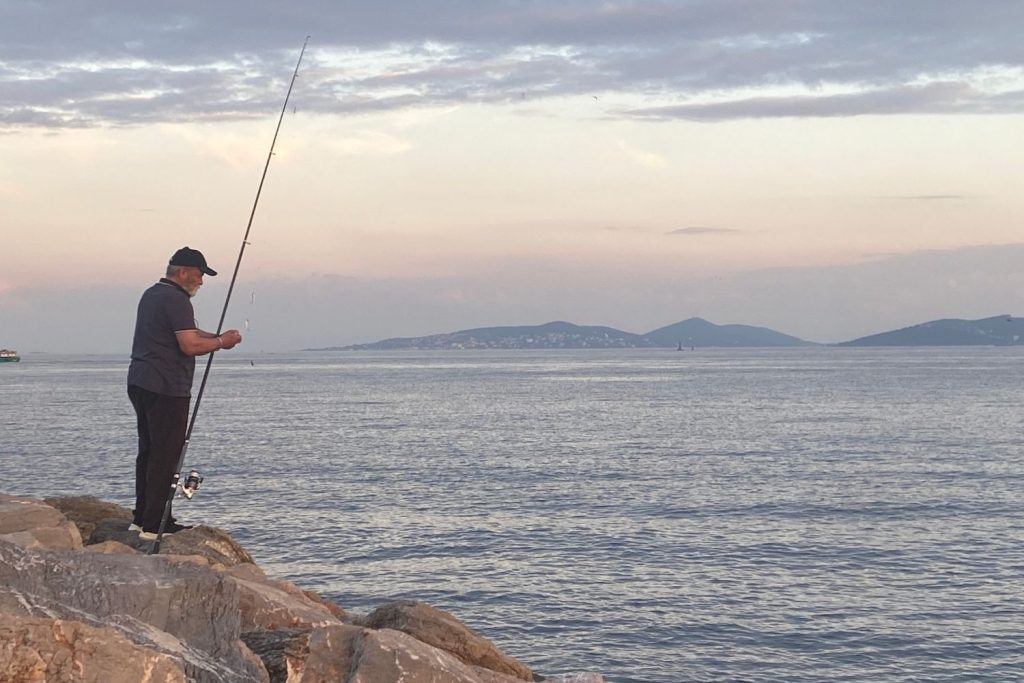 man fishing with princes' islands in the background