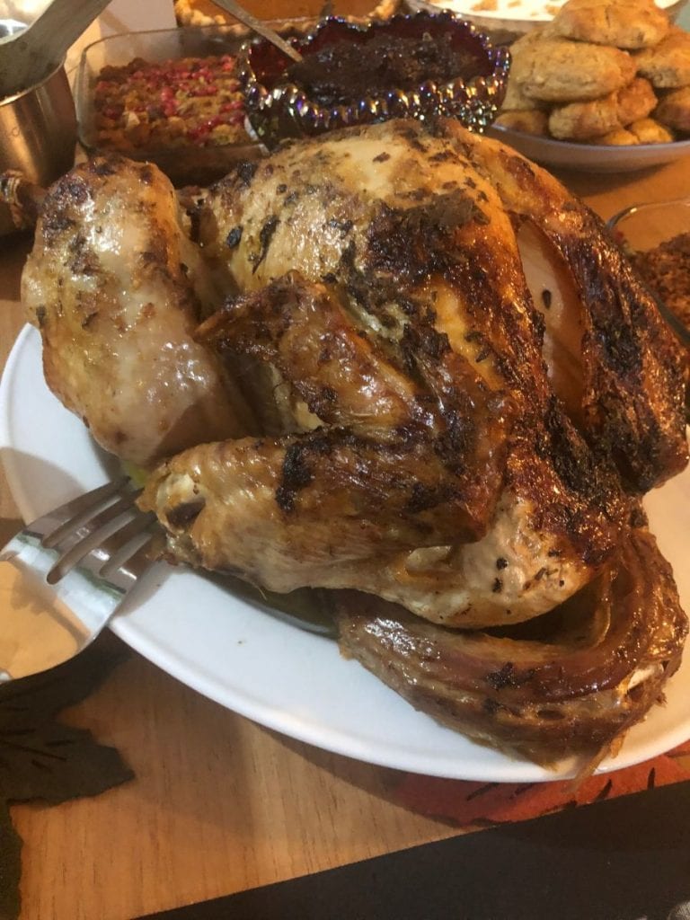Beautifully roasted turkey on a white platter on a butcher block counter