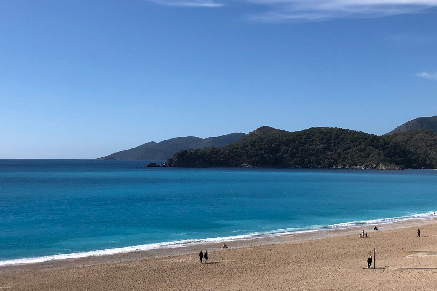 Oludeniz beach, a stop on a sail turkey tour with Contiki, with pristine turquoise waters and a clear sky.