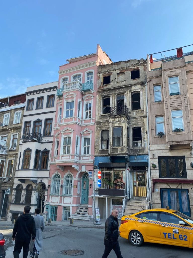 buildings of Istanbul that are so close they are touching. One is run down and they other has been recently painted pink