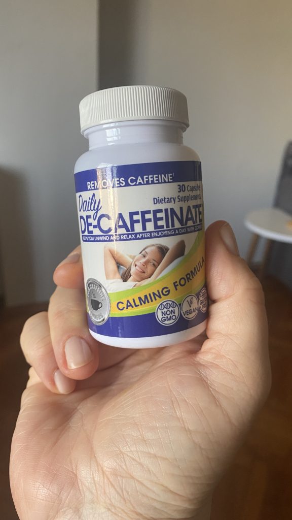 Me holding a bottle of De-Caffinate, a supplement to help remove the caffeine from my body before bed!