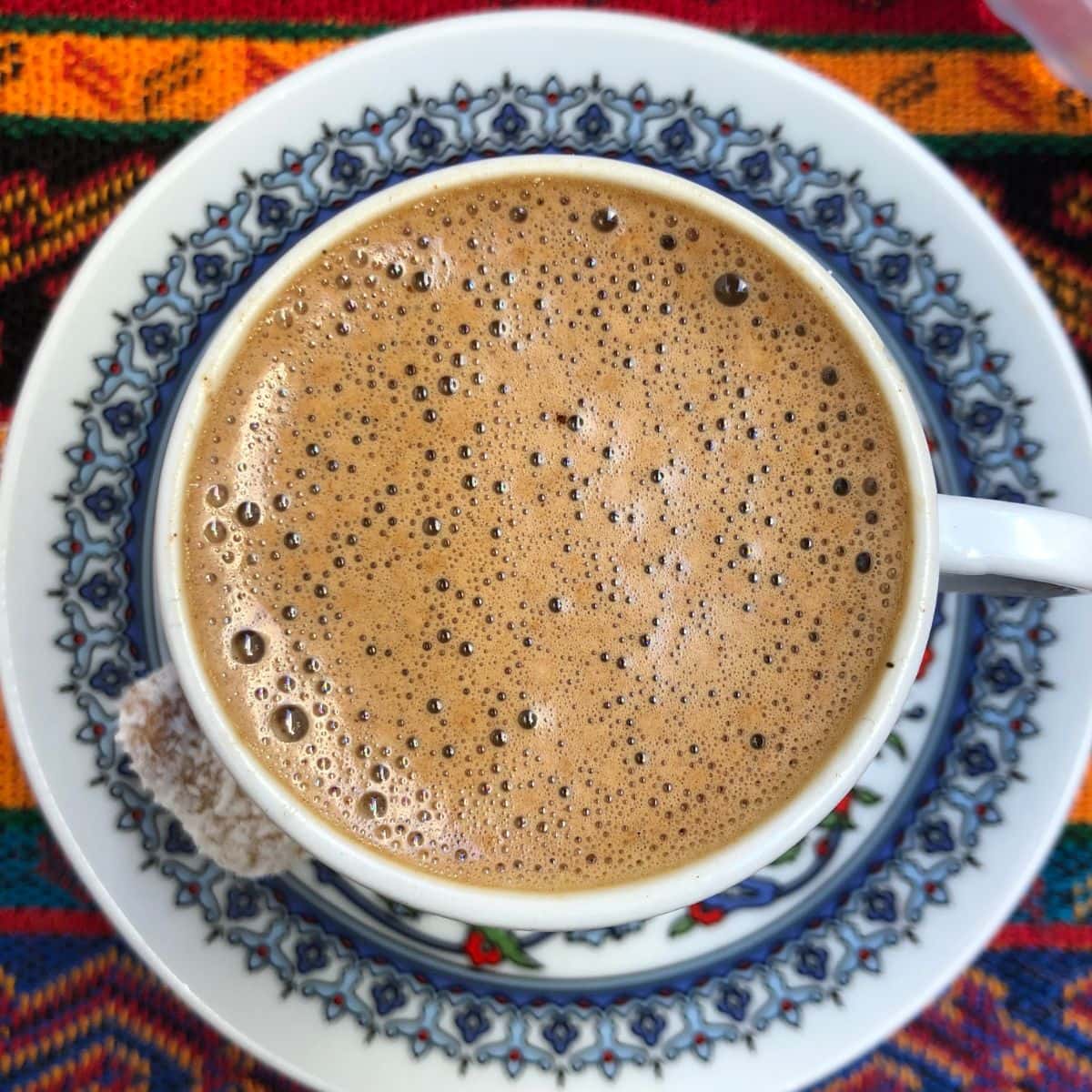 Turkish coffee shot from above to capture the foam on top on a traditional red and blue tulip style saucer