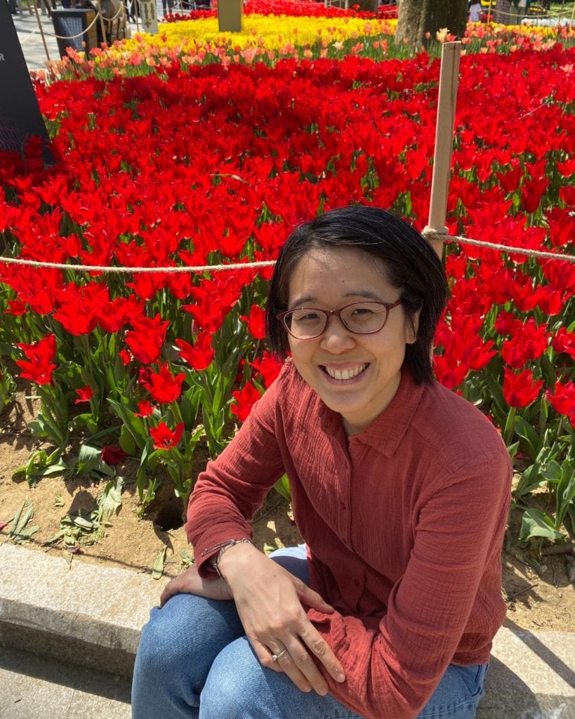 me sitting next to a bed of red flowers.