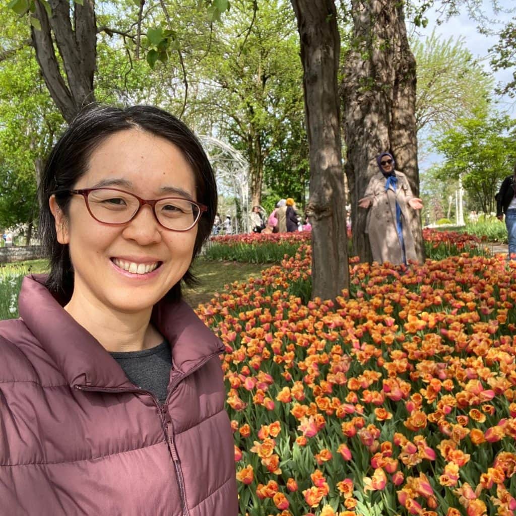 Blog author Michelle posing next to orange tulips at Emirgan Park in Spring