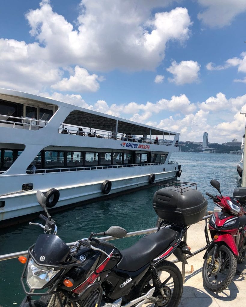 Motorcycles are parked on the dock near a ferry on the Bosphorus