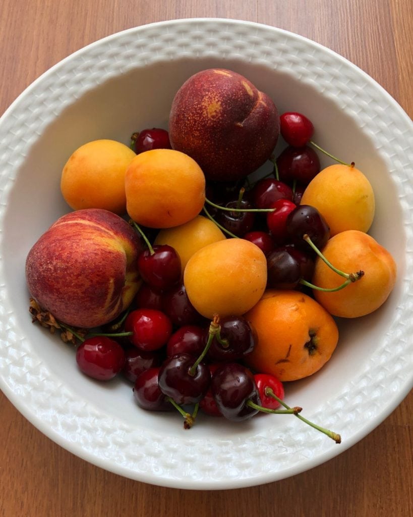 Summer cherries, peaches and apricots in a white bowl