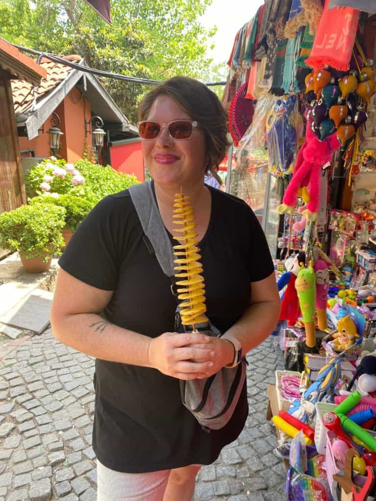 Kimberly holding a spiral of fried potatoes on a stick