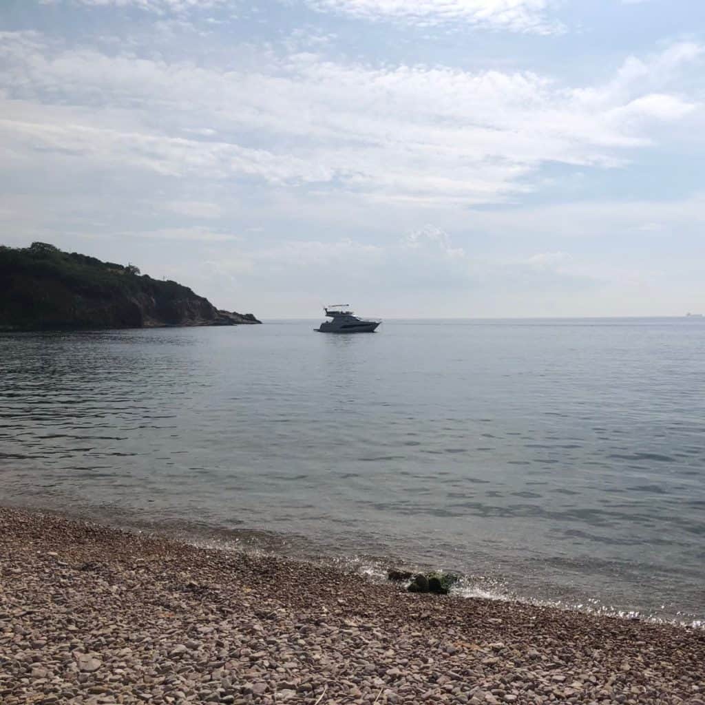 A pebble beach with a boat in the background at Kinaliada in the Princes' Islands, Istanbul.