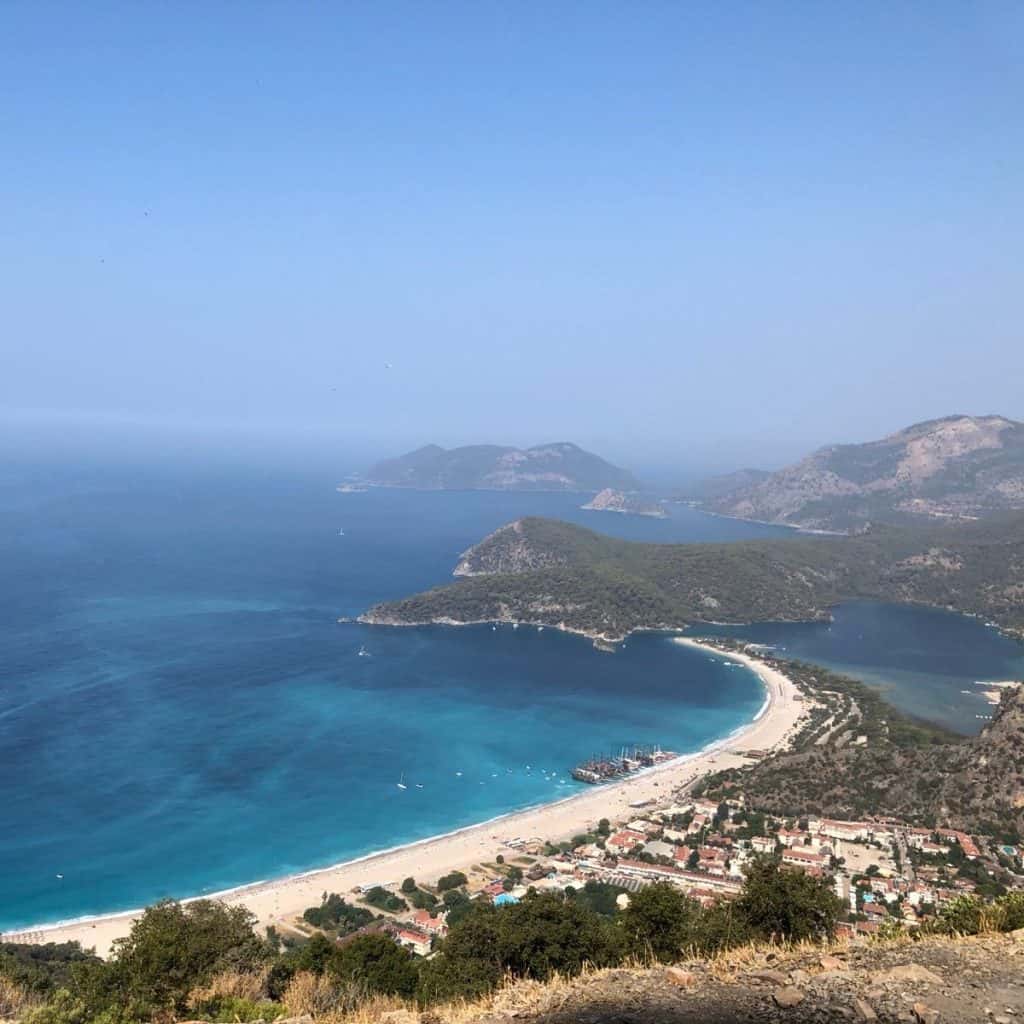 A view of the curved shore and blue waters of Oludeniz Beach, Fethiye from a high vantage point.